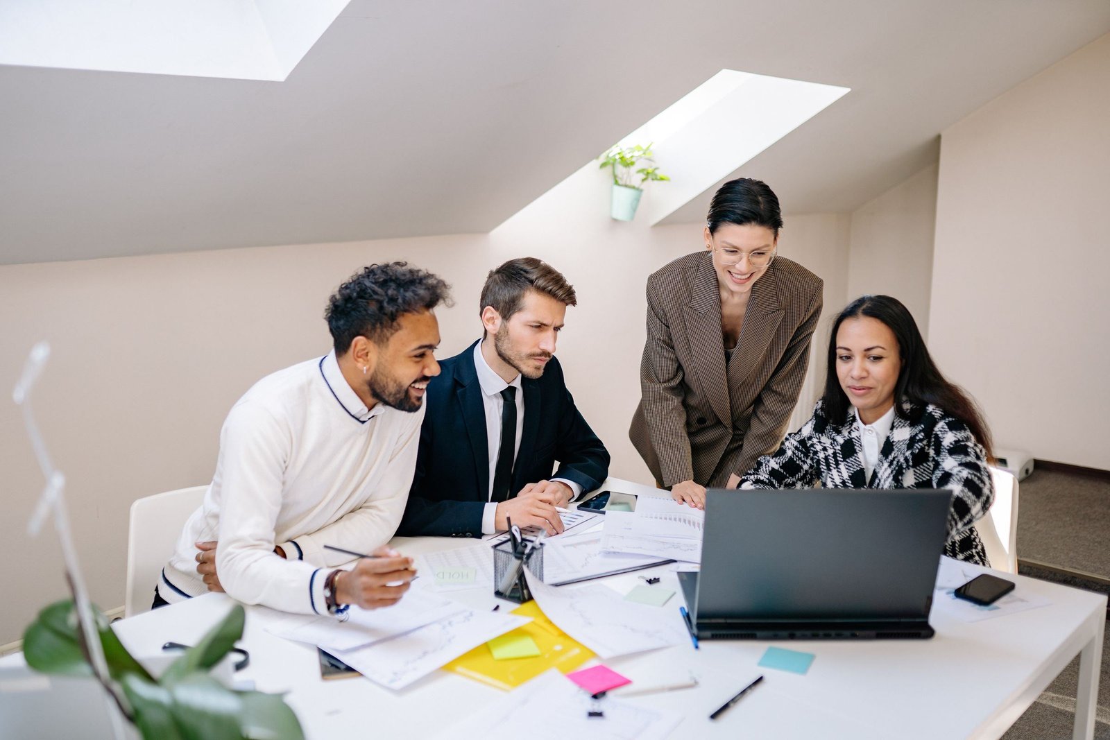 Four colleagues working together around a laptop in a bright office