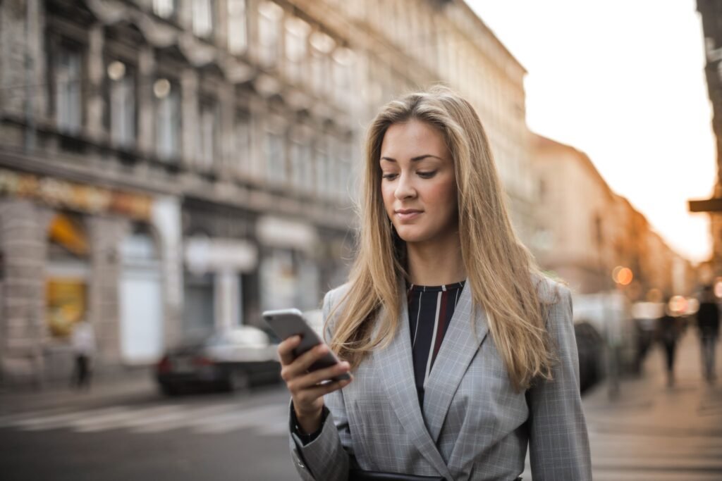 A woman walking on a city street while looking at her smartphone